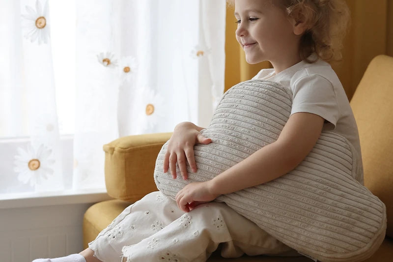 Child cuddling a cream corduroy Cloud Cushion.