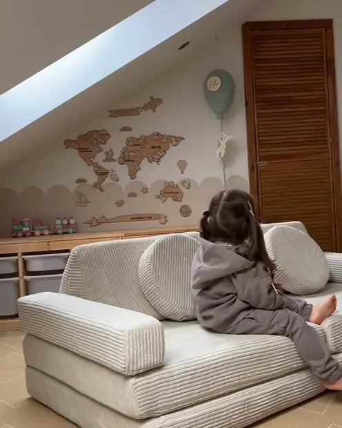 A child playing on the Shappy Pure Corduroy play sofa in a bright attic room