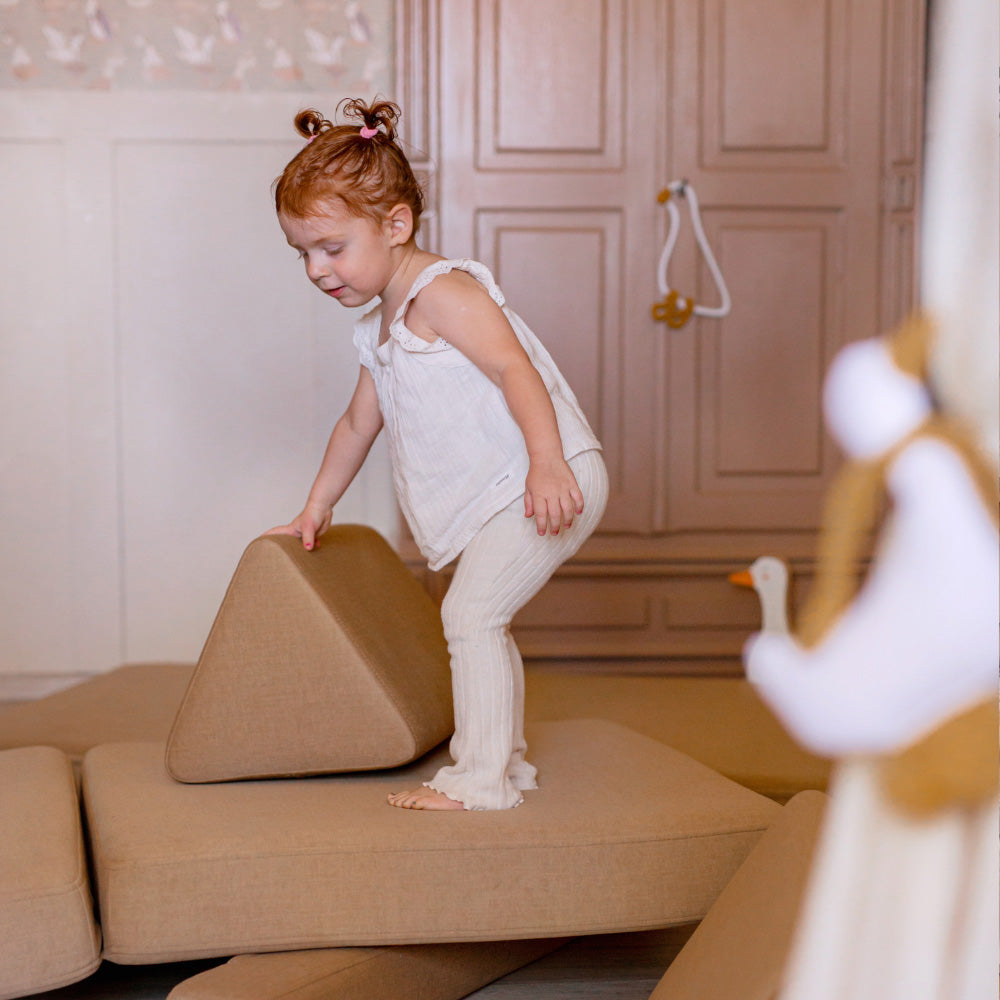Children playing with colorful modular Shappy play sofa pieces in a bright living room