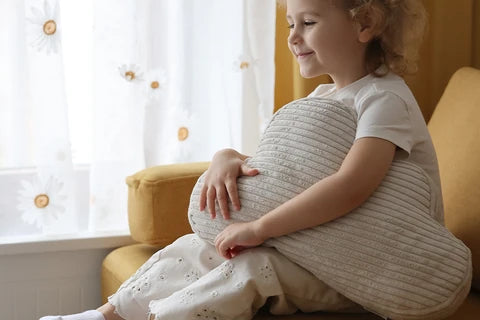 Child cuddling a cream corduroy Cloud Cushion.