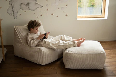Child relaxing in a Kumo Chair with a matching Kumo Ottoman, sold separately.