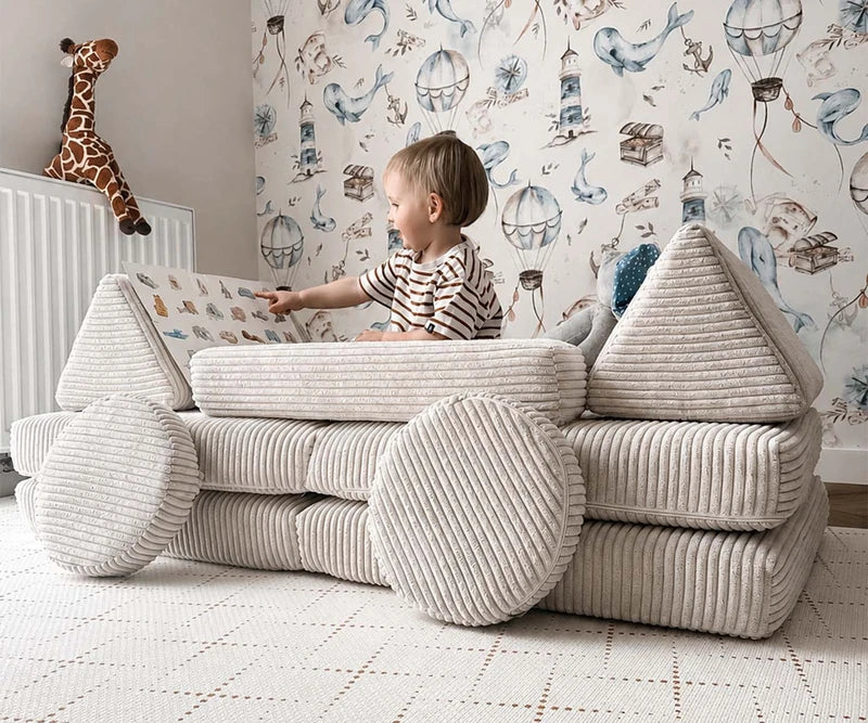 Child reading on a cream corduroy Mini play sofa arranged for play.