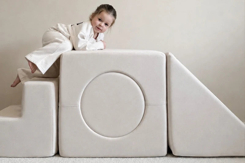 Child playing on a cream Playset with steps, a circular insert and a slide.