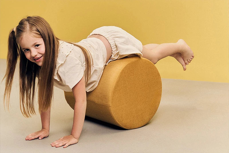 Child playing on a mustard-yellow round pouf.