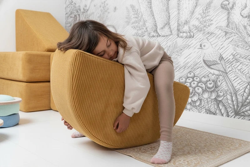 Child leaning over a mustard-yellow corduroy Rocker.