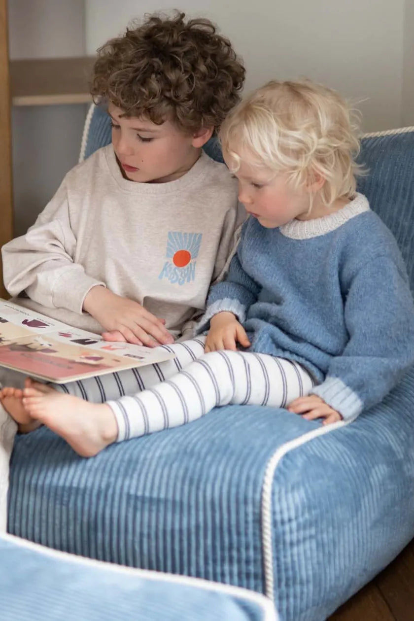 Two children reading together in Kumo Chair Sky Sugar