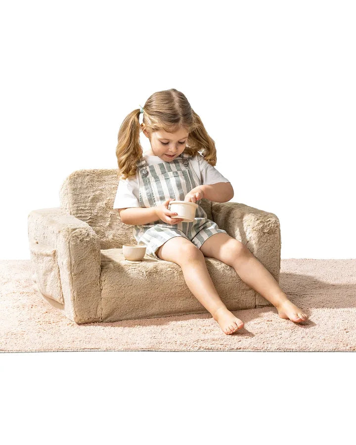Une fille assise dans le Lumi Chair Bunny coloris Toffee