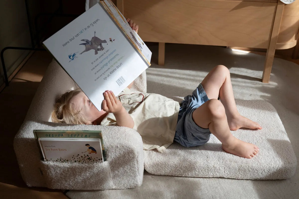 Child reading on Lumi Chair Teddy in Soft Cream, unfolded