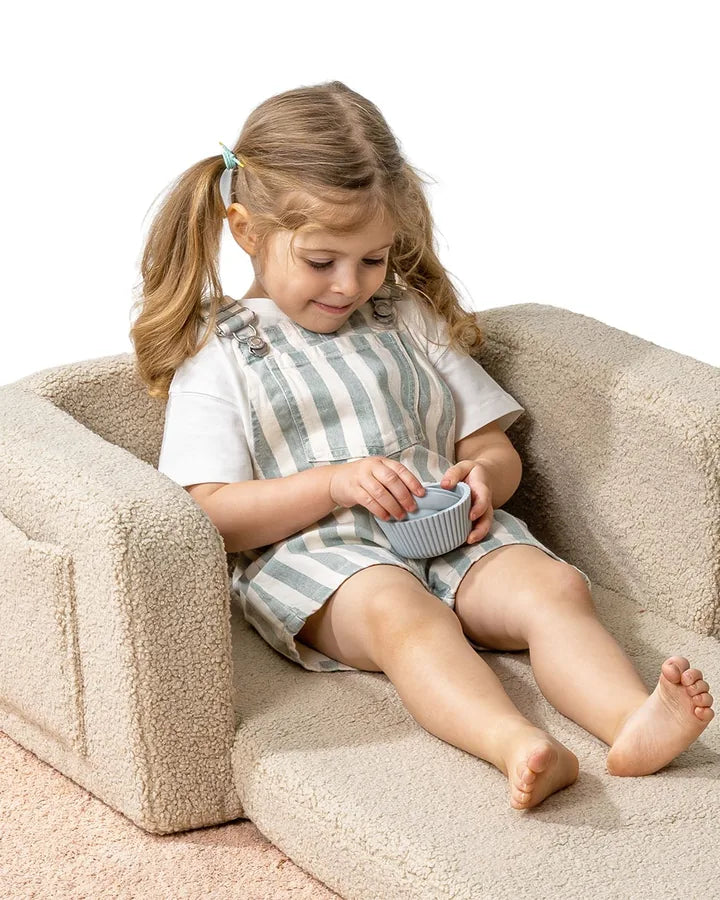 Girl lying on Lumi Chair Teddy in Light Beige, unfolded