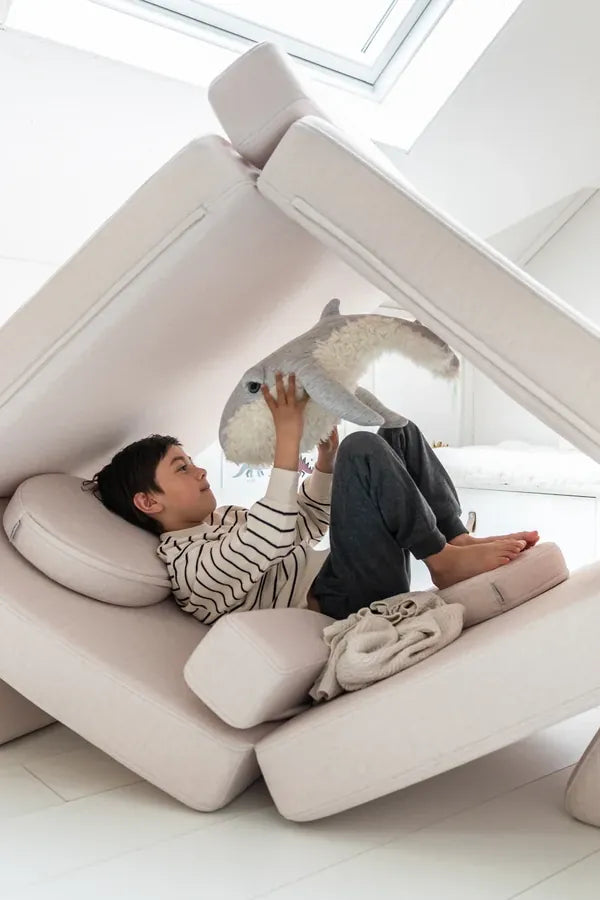 Child resting in a hideaway built from Play Sofa Original Soft Beige
