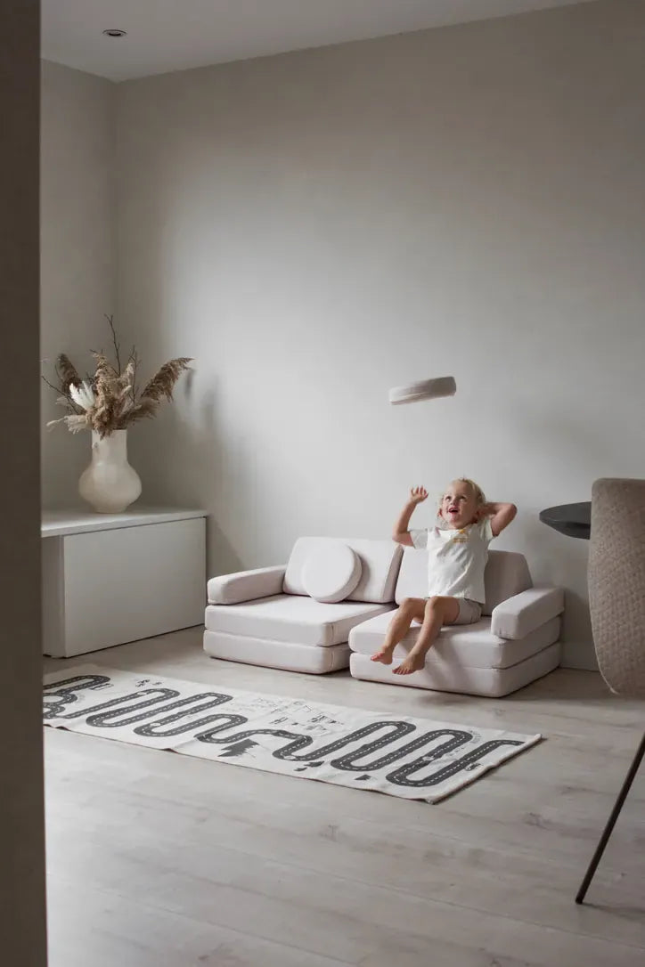 Child relaxing on Play Sofa Original Mini in Soft Beige in a living room