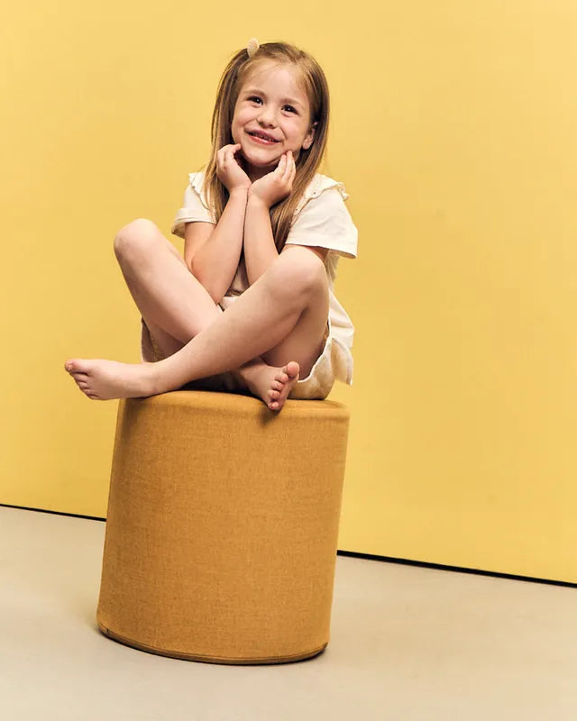 Girl sitting cross-legged on Shappy Pouf Ultra Plush Mustard