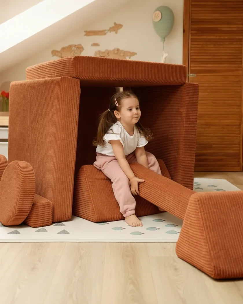 Een meisje zit in een hut gebouwd van een speelbank van Corduroy in Cinnamon
