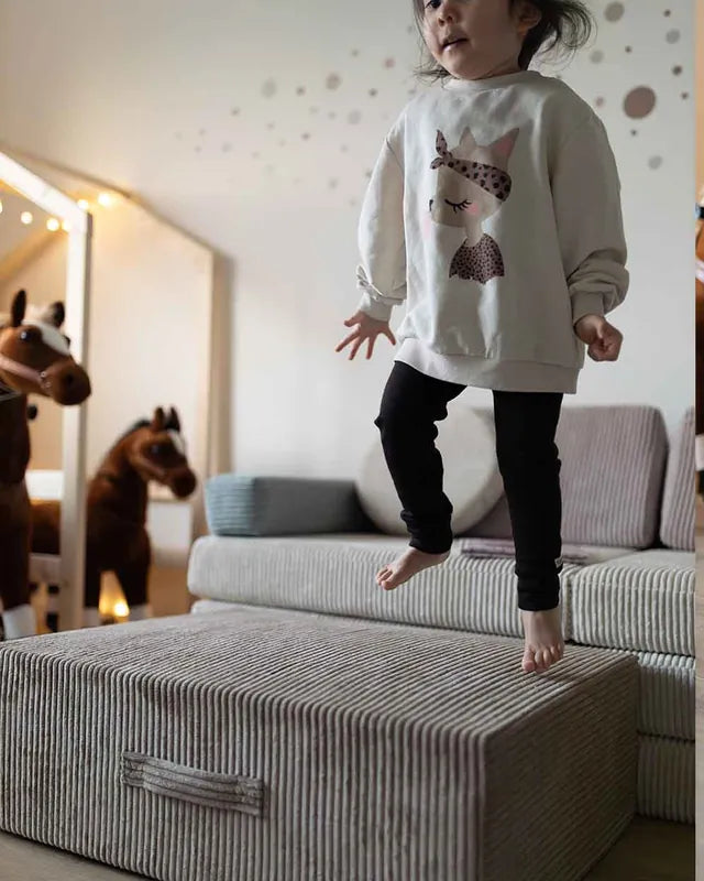 Girl jumping on Trampoline Pure Corduroy next to the Play Sofa