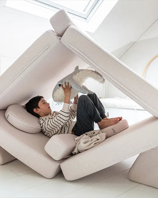 Boy relaxing in a tent built from Play Sofa Original Soft Beige