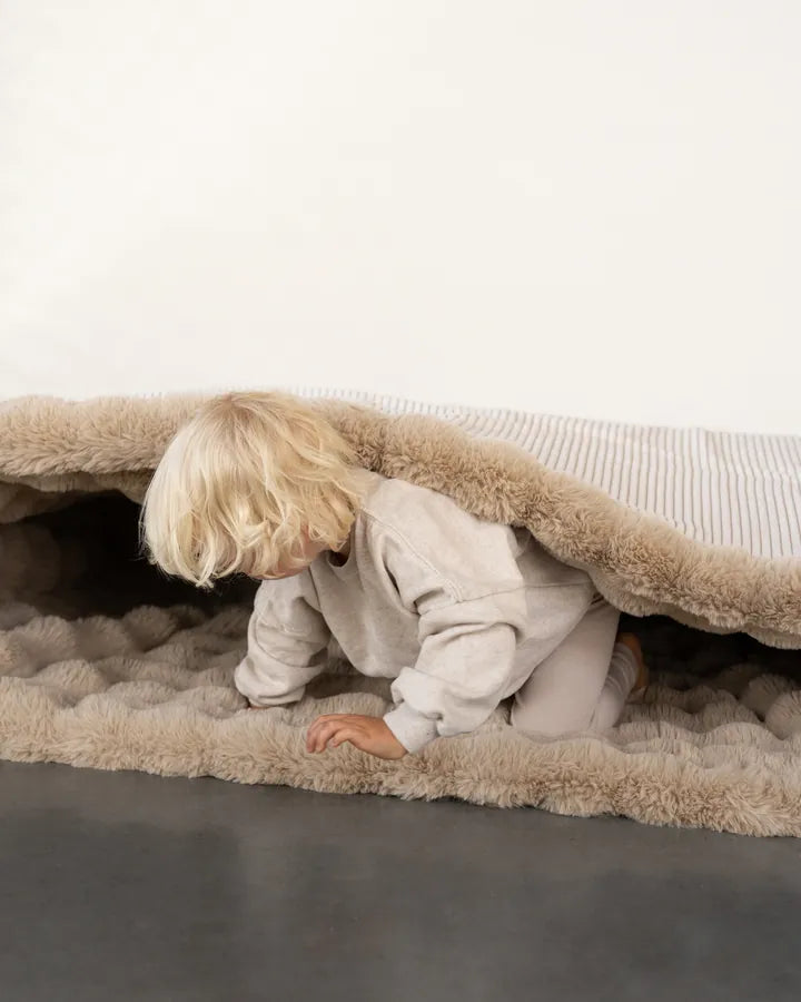 Kind auf dem zur Matte aufgeklappten Snuggle Bag