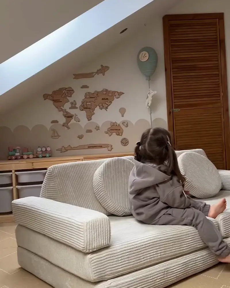 A child playing on the Shappy Pure Corduroy play sofa in a bright attic room