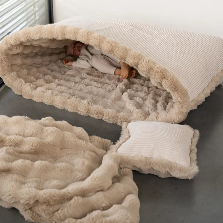 Snuggle Bag mit einem Kind darin, daneben Snuggle Blanket und Snuggle Cushion