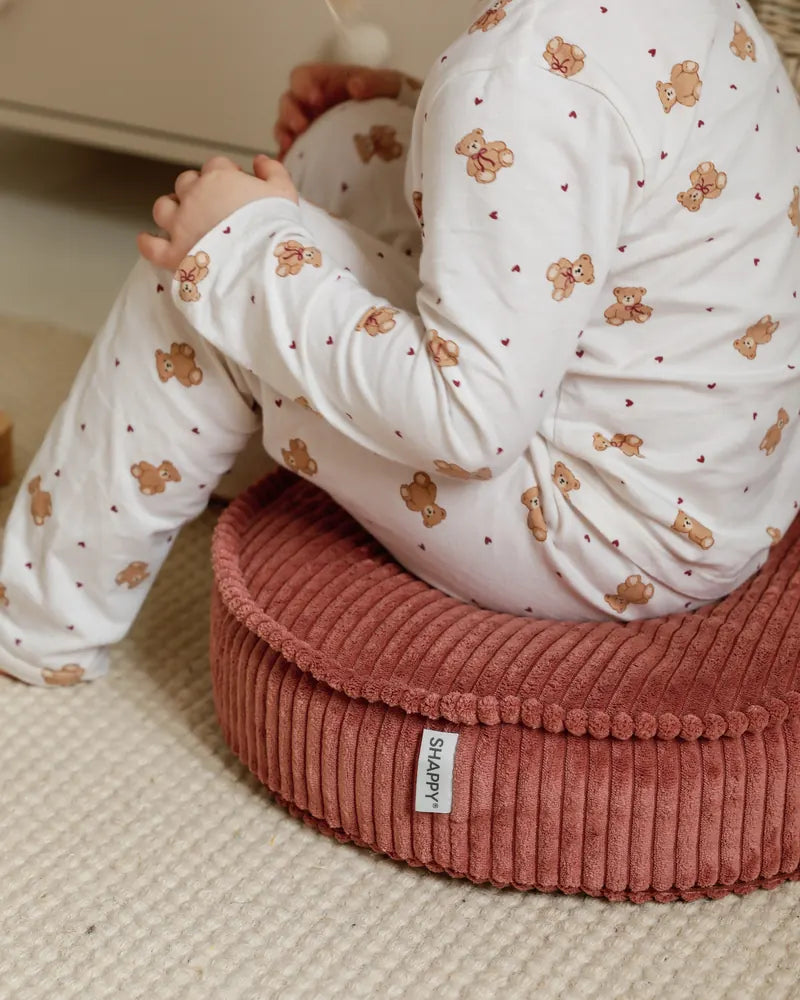 Close-up of a child sitting on a Yuka Pouf Mini in Rose