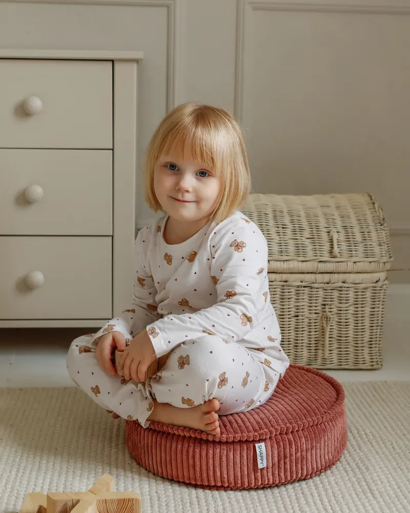 Child sitting on a Yuka Pouf Mini in Rose