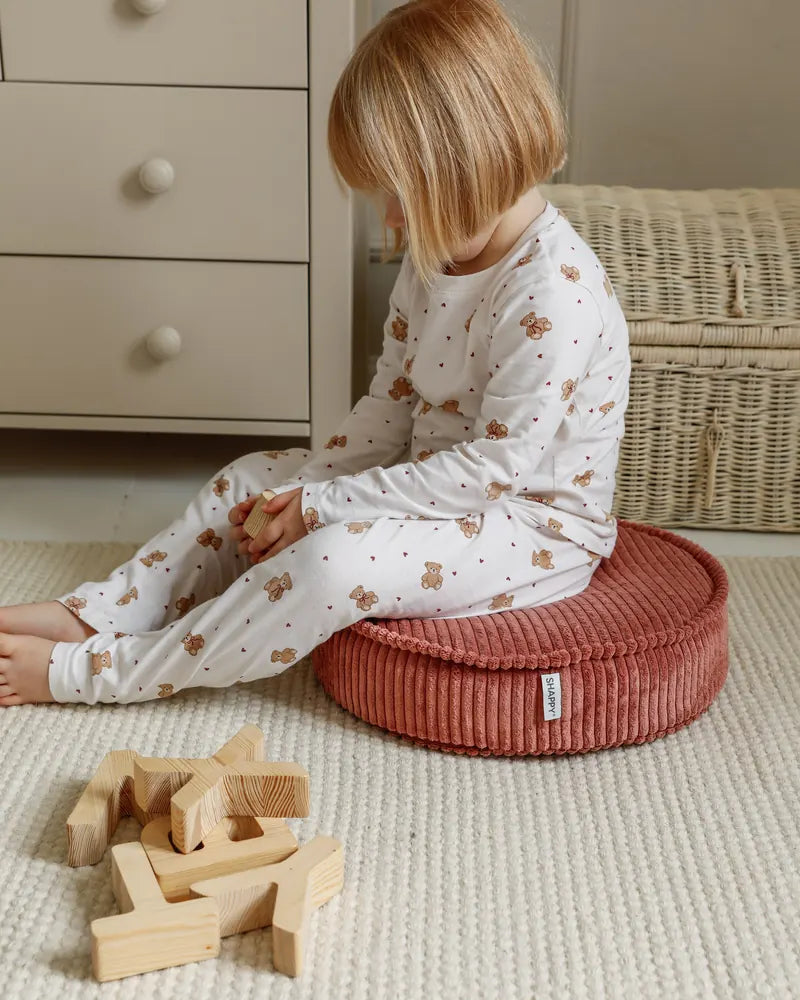 Child playing with wooden blocks next to a Yuka Pouf Mini in Rose