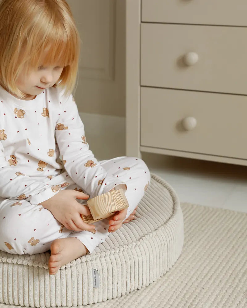 Child playing with wooden blocks on a Yuka Pouf in Vanilla